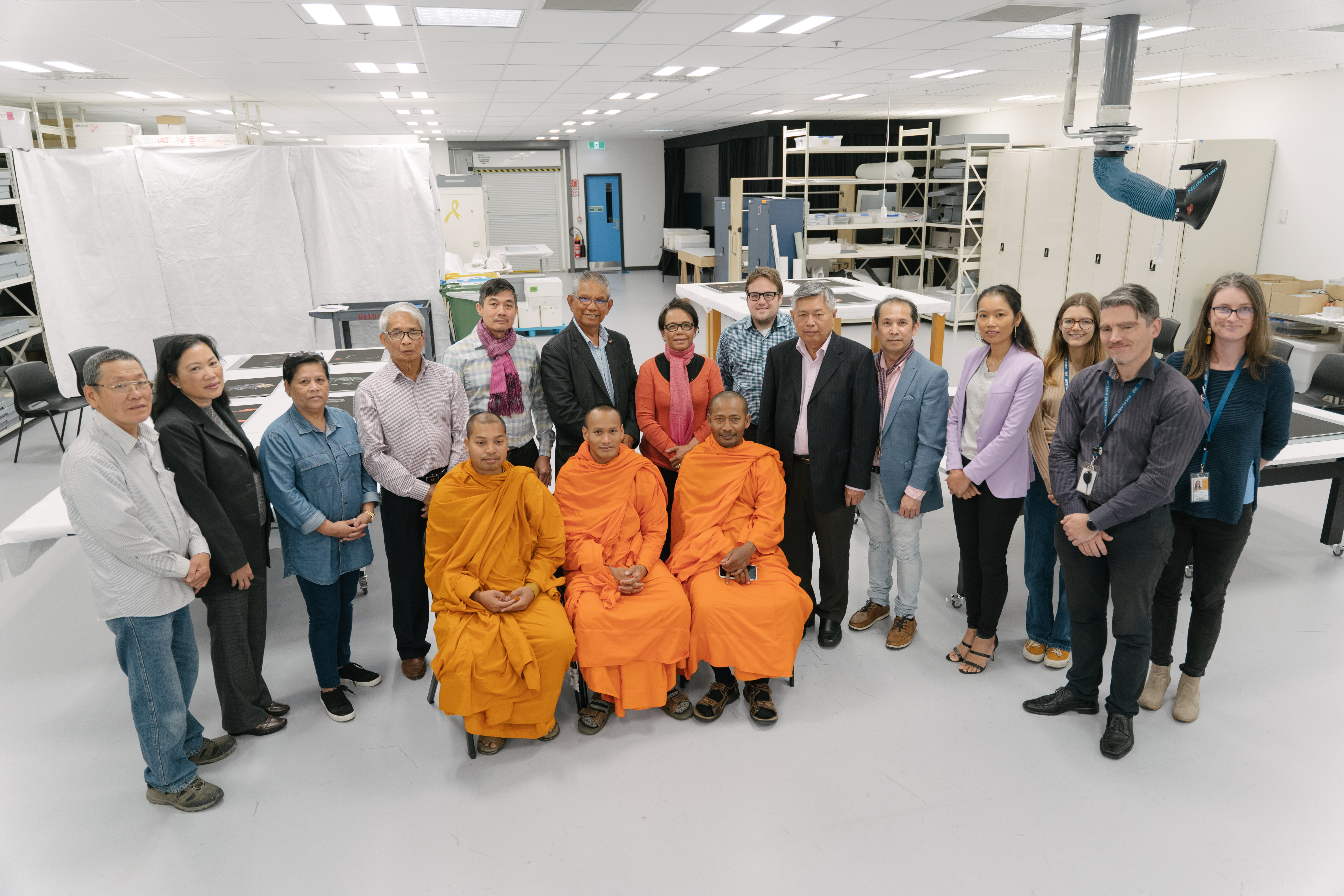 Full Image Three monks and a number of Cambodian community members pose with museum staff in the museum storage room