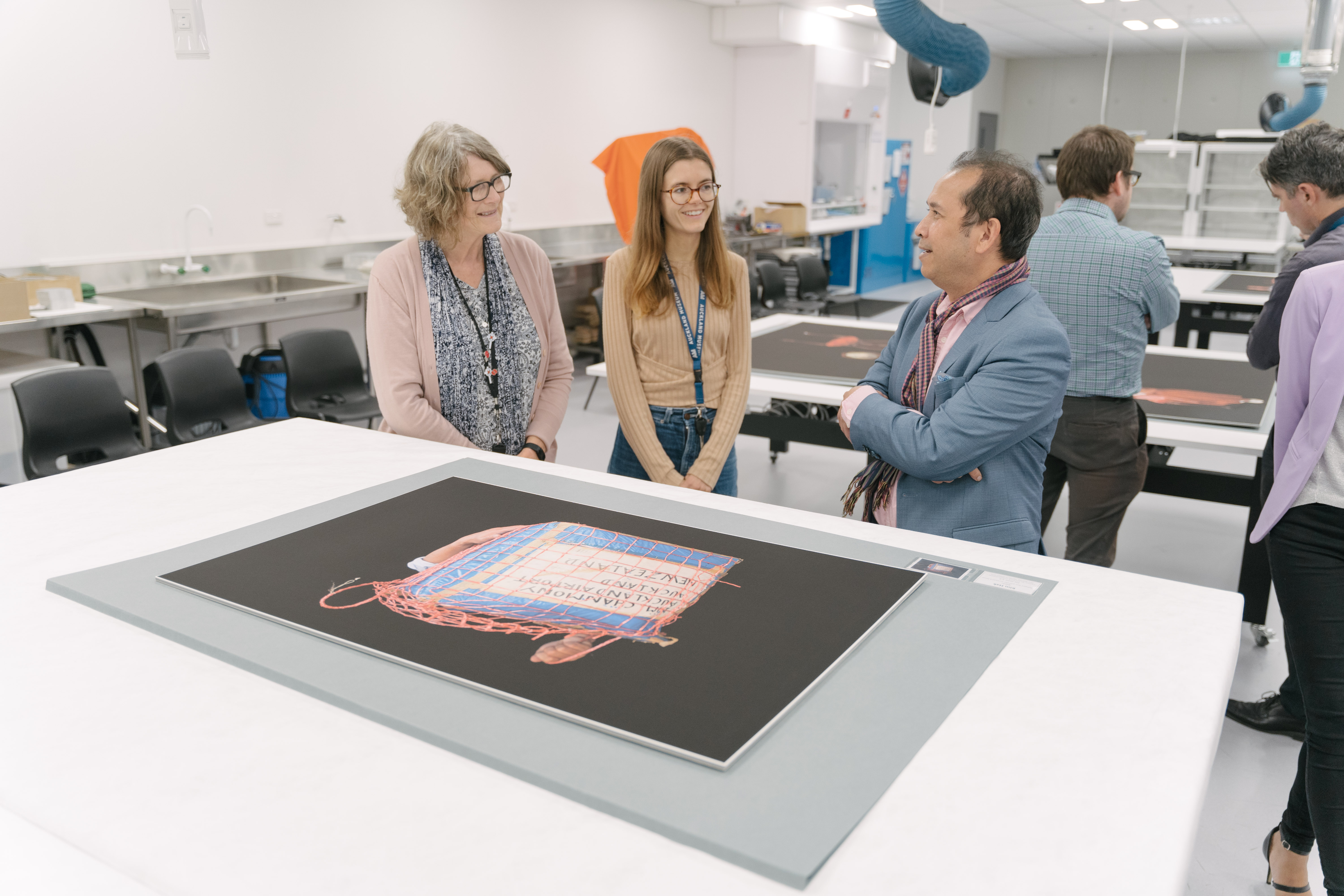 Full Image A member of the Cambodian community and two Museum staff members view Kim Hak's works containing the box in which refugees would carry their belongings