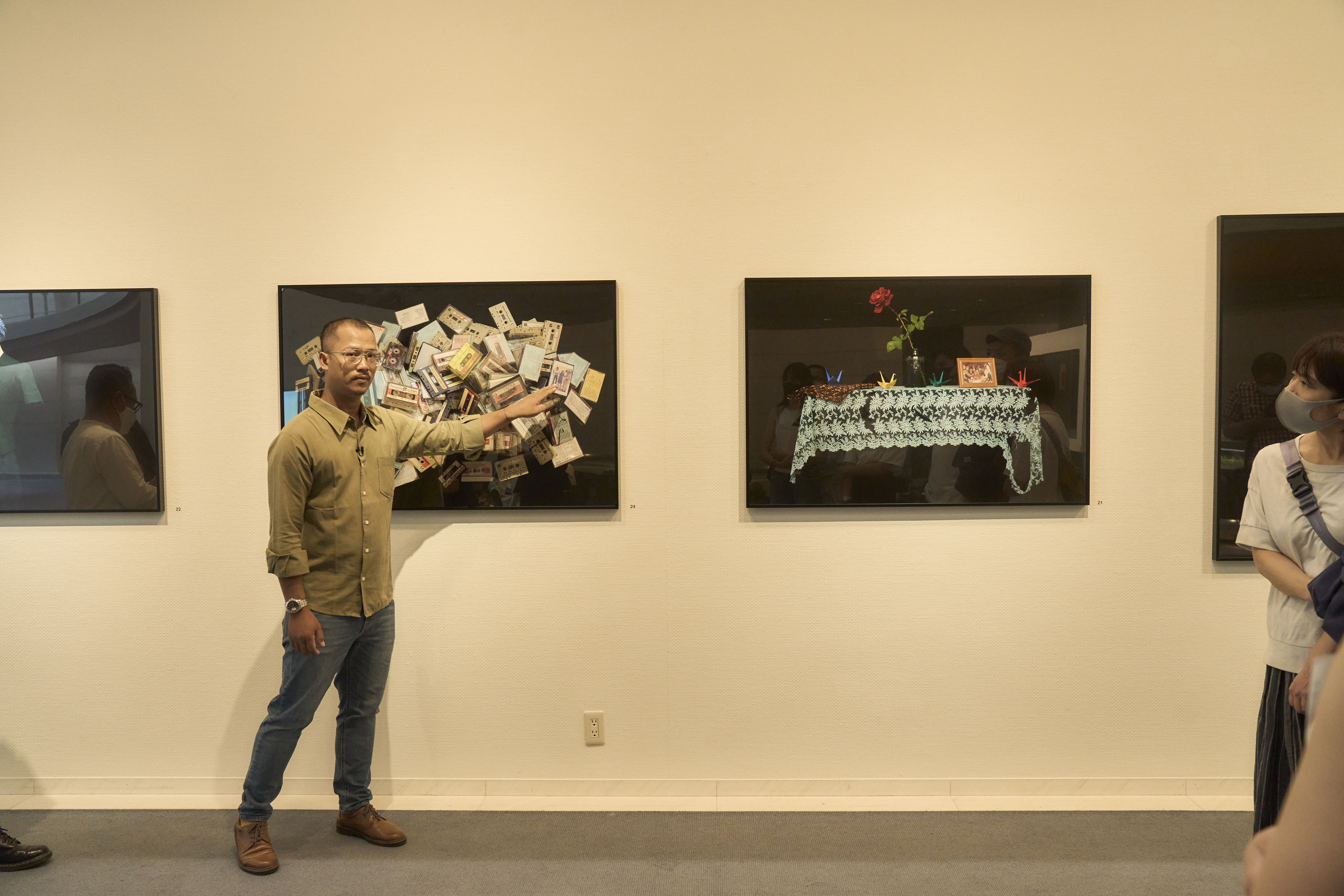 Full Image Artist Kim Hak points at one of his photographs during a gallery tour while onlookers listen