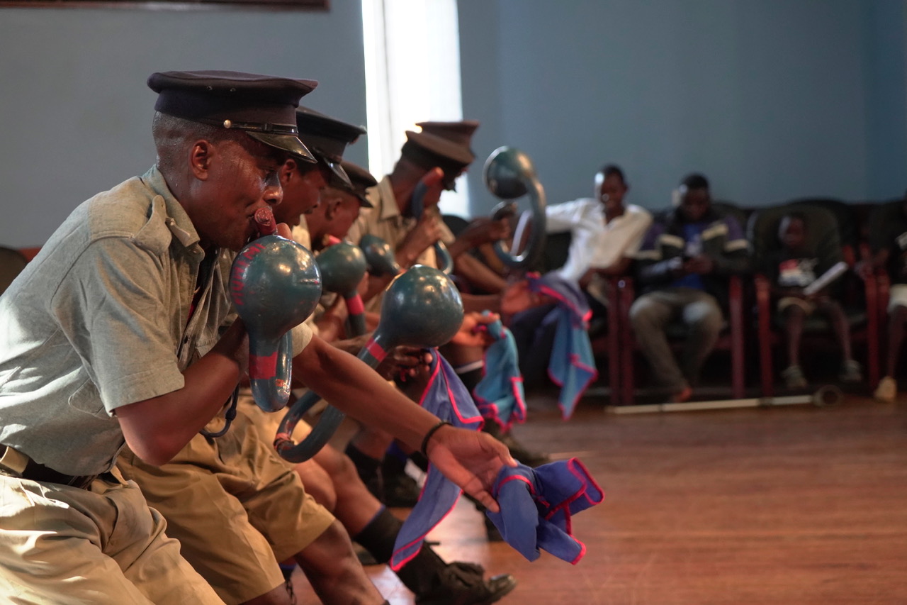 Full Image Several men performing a traditional Malawian dance